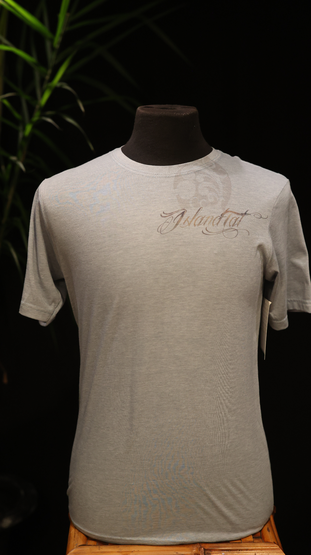 Front view of a light heather gray shirt with subtle Islandtat script printed across the upper chest.