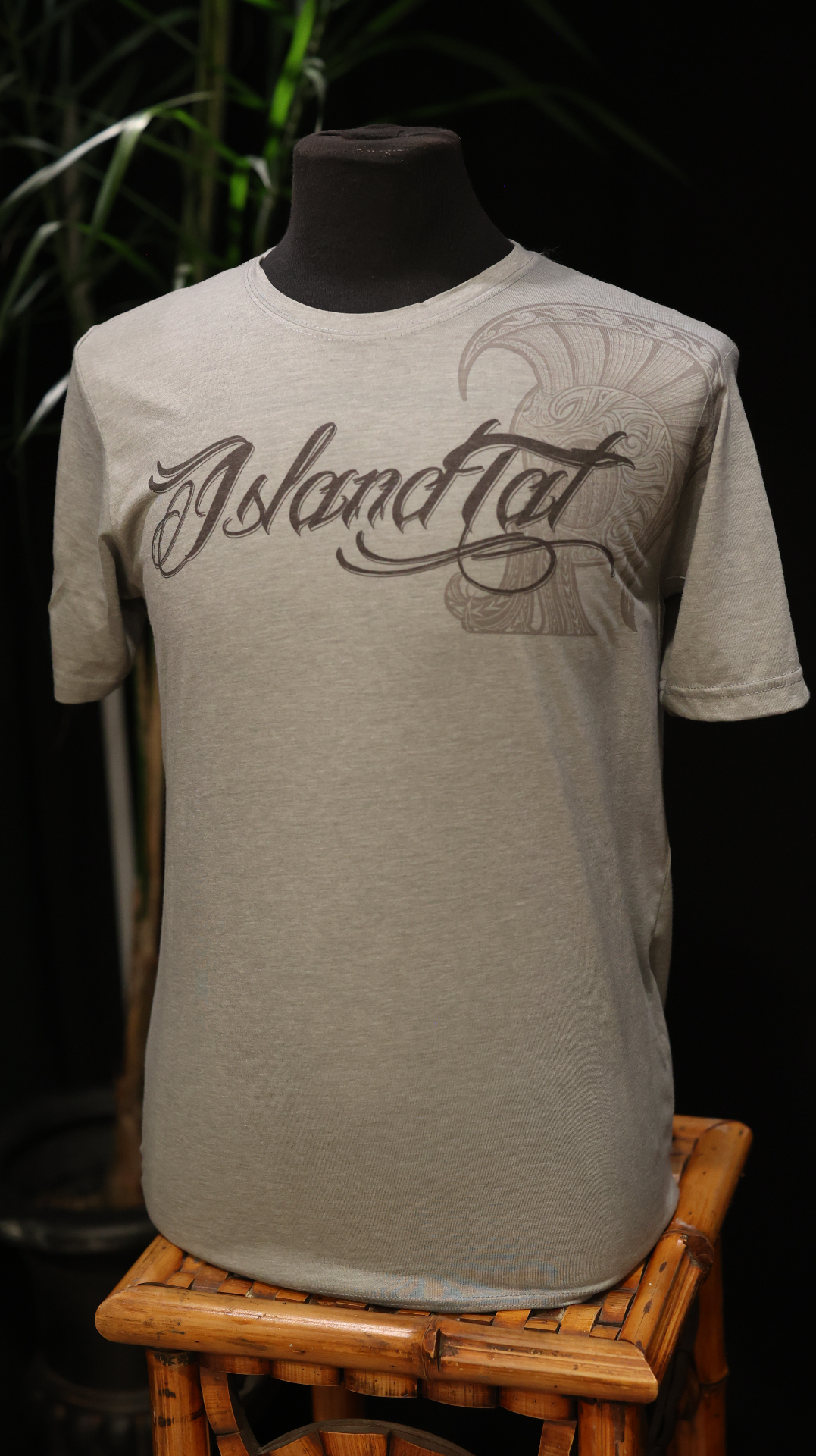 Front view of a Heather Gray shirt with Islandtat script across the chest and a large helmet artwork flowing from the shoulder.
