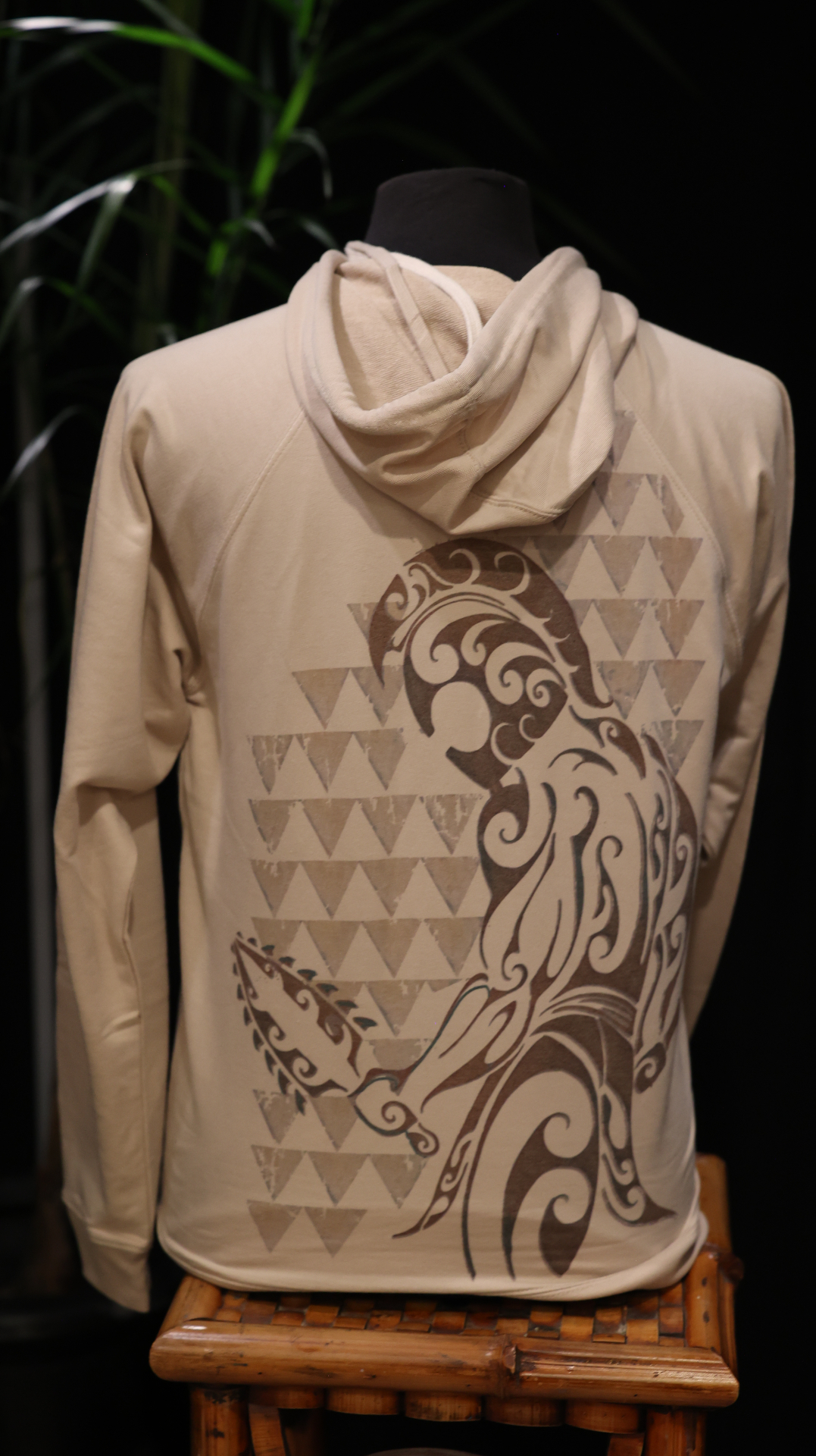 Back view of a cream hoodie with a large Polynesian wave artwork printed on the back.