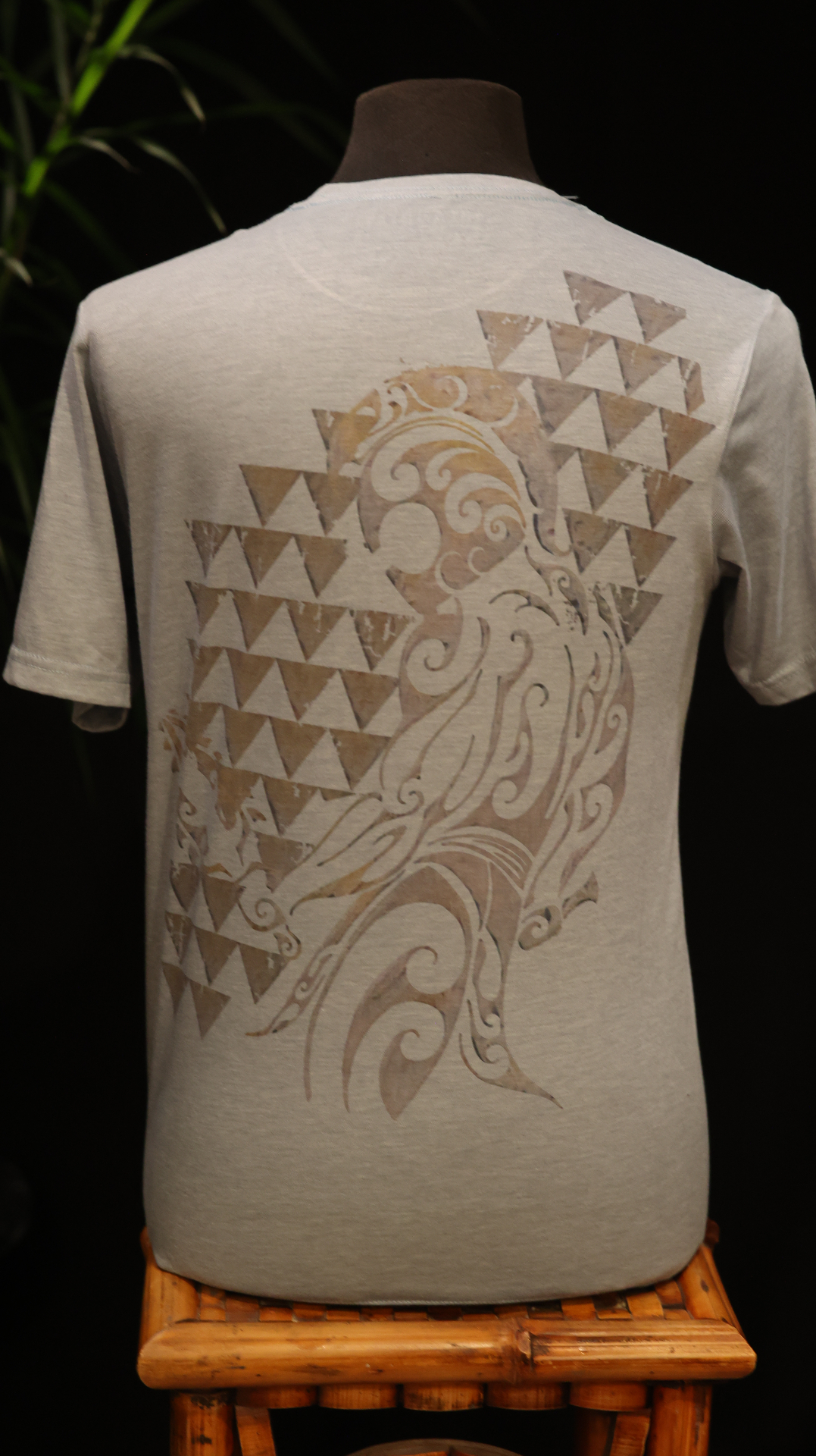 Back view of a light heather gray shirt with a large Polynesian-inspired wave graphic.